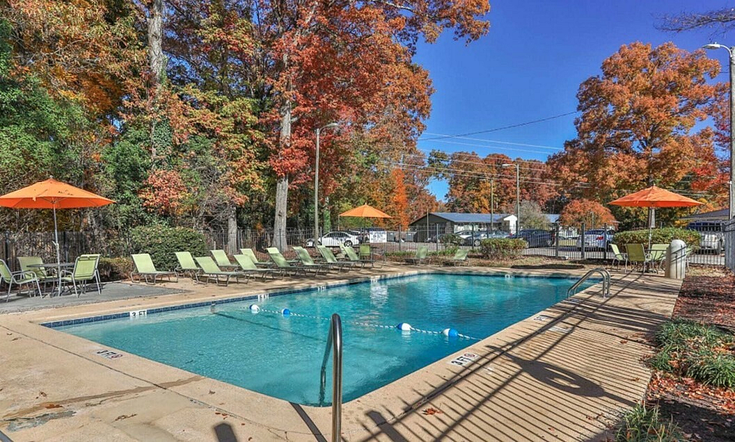 Inviting outdoor pool with vibrant fall foliage and comfortable sun loungers, perfect for a relaxing retreat in nature.
