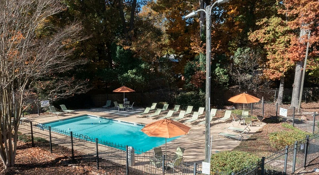 Inviting outdoor area with a sparkling blue pool, surrounded by sunlit loungers and vibrant autumn foliage.