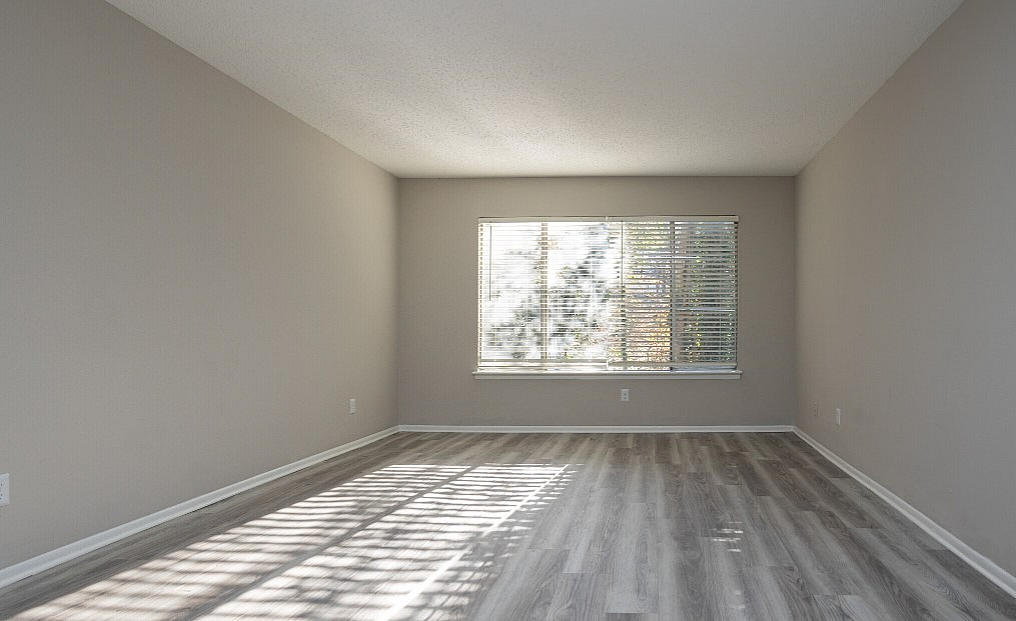 Bright, spacious room with elegant wood flooring and large window for abundant natural light.