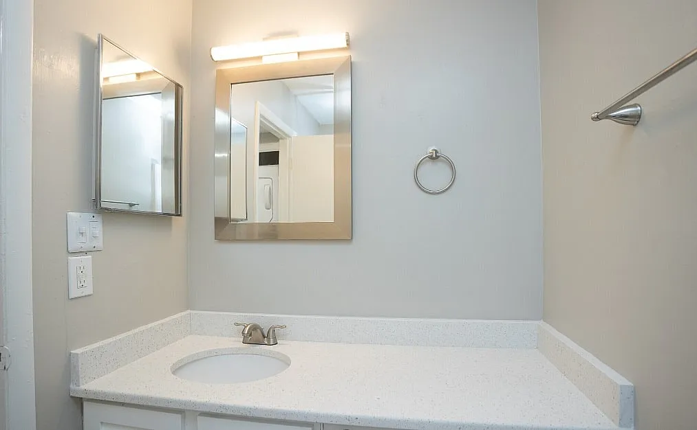 Contemporary bathroom with a sleek countertop, modern faucet, and stylish mirror, offering a bright and clean design.