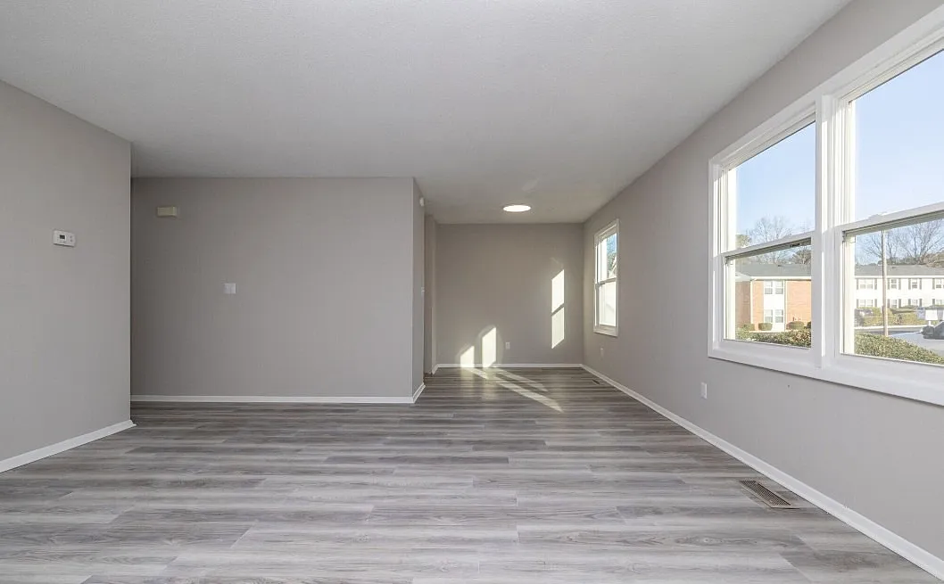 Bright, modern apartment with sleek gray flooring and large windows offering scenic views.