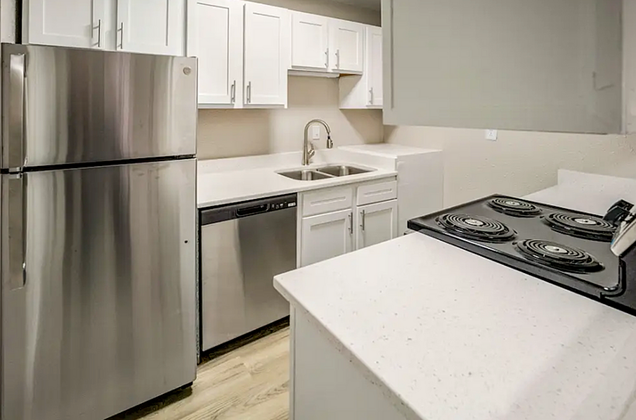 Modern kitchen with sleek stainless steel appliances, elegant white cabinetry, and polished countertops.