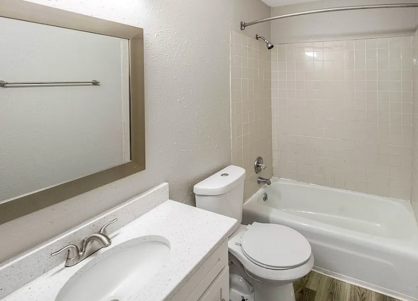 Modern bathroom featuring a pristine bathtub, sleek vanity with a large mirror, and elegant tile flooring, offering a serene spa-like atmosphere.