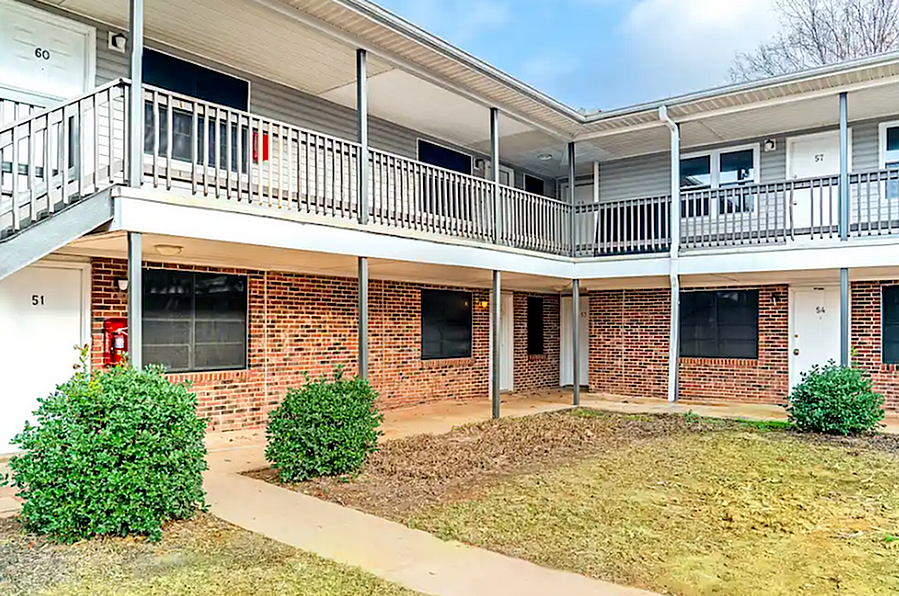 Inviting brick apartment building with charming balcony railings and well-kept greenery, offering a welcoming neighborhood vibe.