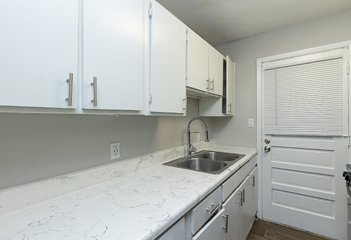 Chic kitchen with sleek white cabinets and elegant marble countertops, complemented by a modern stainless steel sink.
