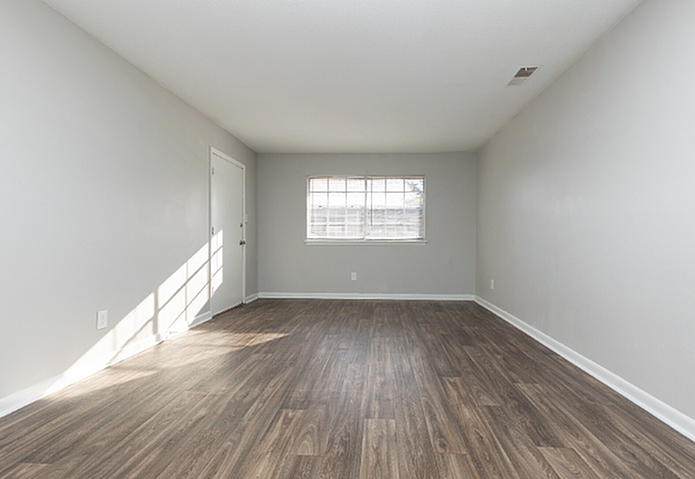 Bright, contemporary living space with elegant wood flooring, ample natural light, and freshly painted white walls.