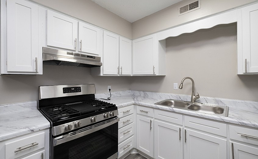 Modern kitchen with sleek stainless steel appliances, elegant white cabinetry, and polished marble countertops.