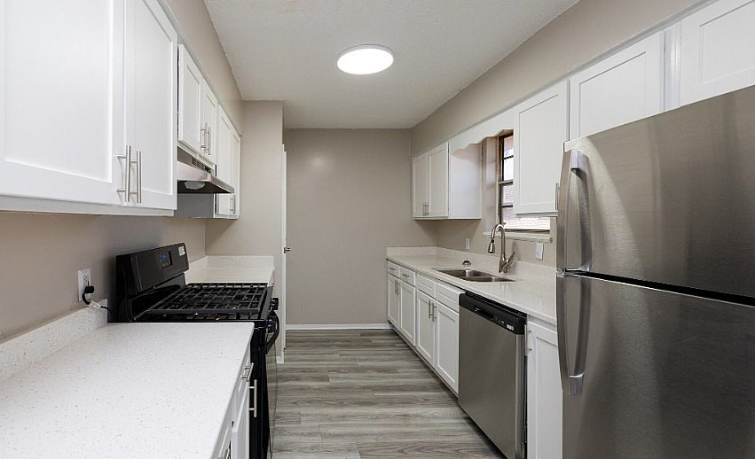 Modern kitchen with stainless steel appliances, sleek white cabinets, and elegant wood flooring.