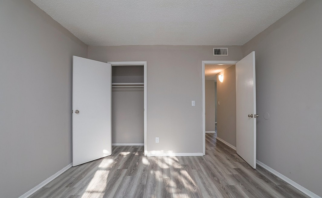 Bright and inviting room with modern laminate flooring, fresh paint, and ample closet space.