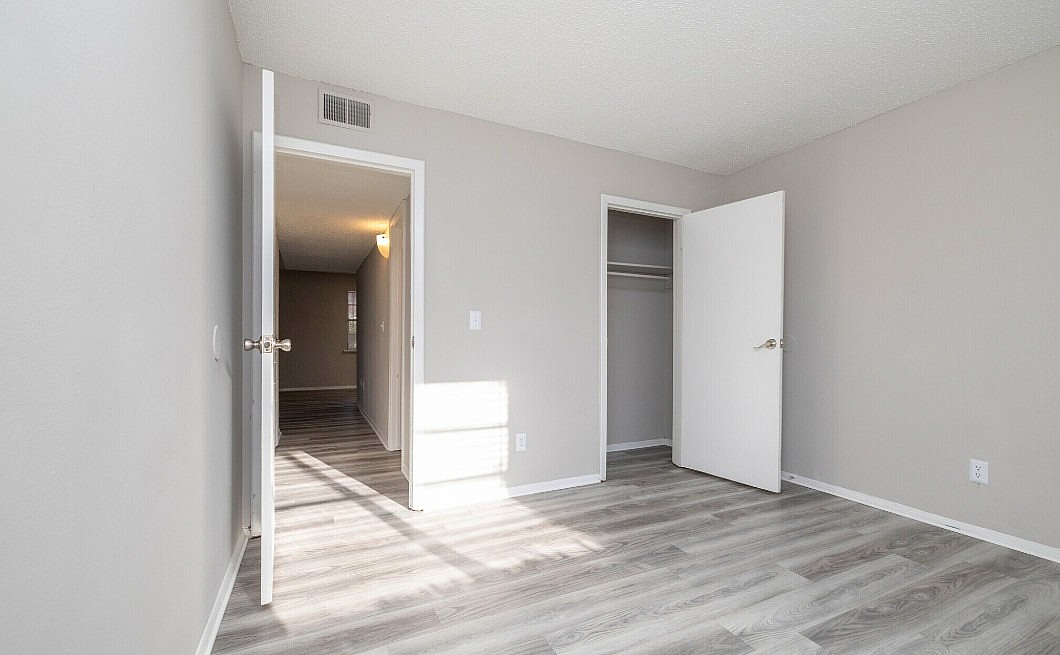Bright and spacious bedroom with modern flooring, open closet, and ample natural light.