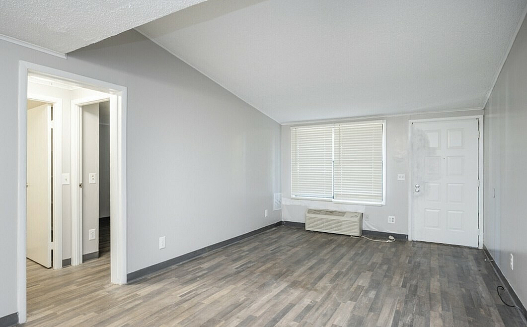 Bright and inviting living space with modern wooden flooring and large windows, perfect for comfort and style.