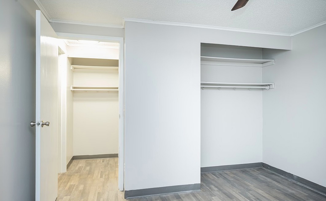 Bright, spacious closet with open shelving and sleek wooden flooring, perfect for all your storage needs.