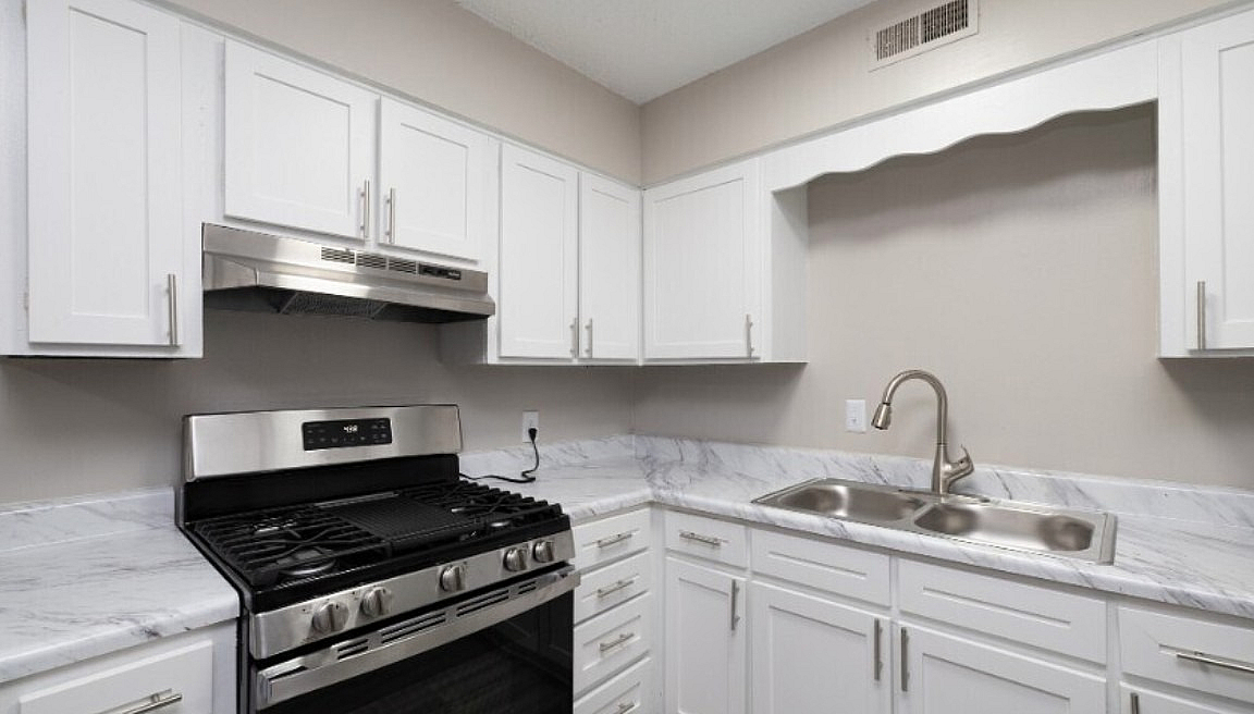Modern kitchen with sleek stainless steel appliances, elegant white cabinetry, and luxurious marble countertops.