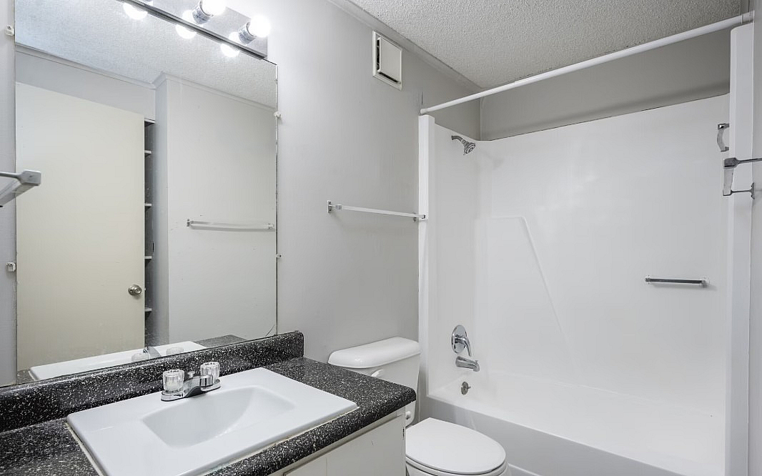 Bright and modern bathroom featuring elegant fixtures, a sleek vanity, and a pristine bathtub, perfect for relaxation and refreshment.