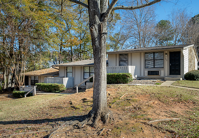 Charming single-story home with large windows and a welcoming facade, nestled in a serene, tree-lined neighborhood.