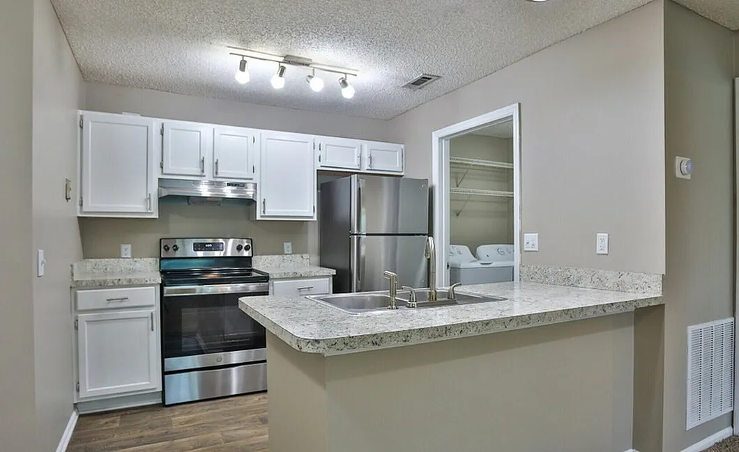 Modern kitchen with sleek stainless steel appliances, elegant white cabinetry, and a stylish granite countertop island.