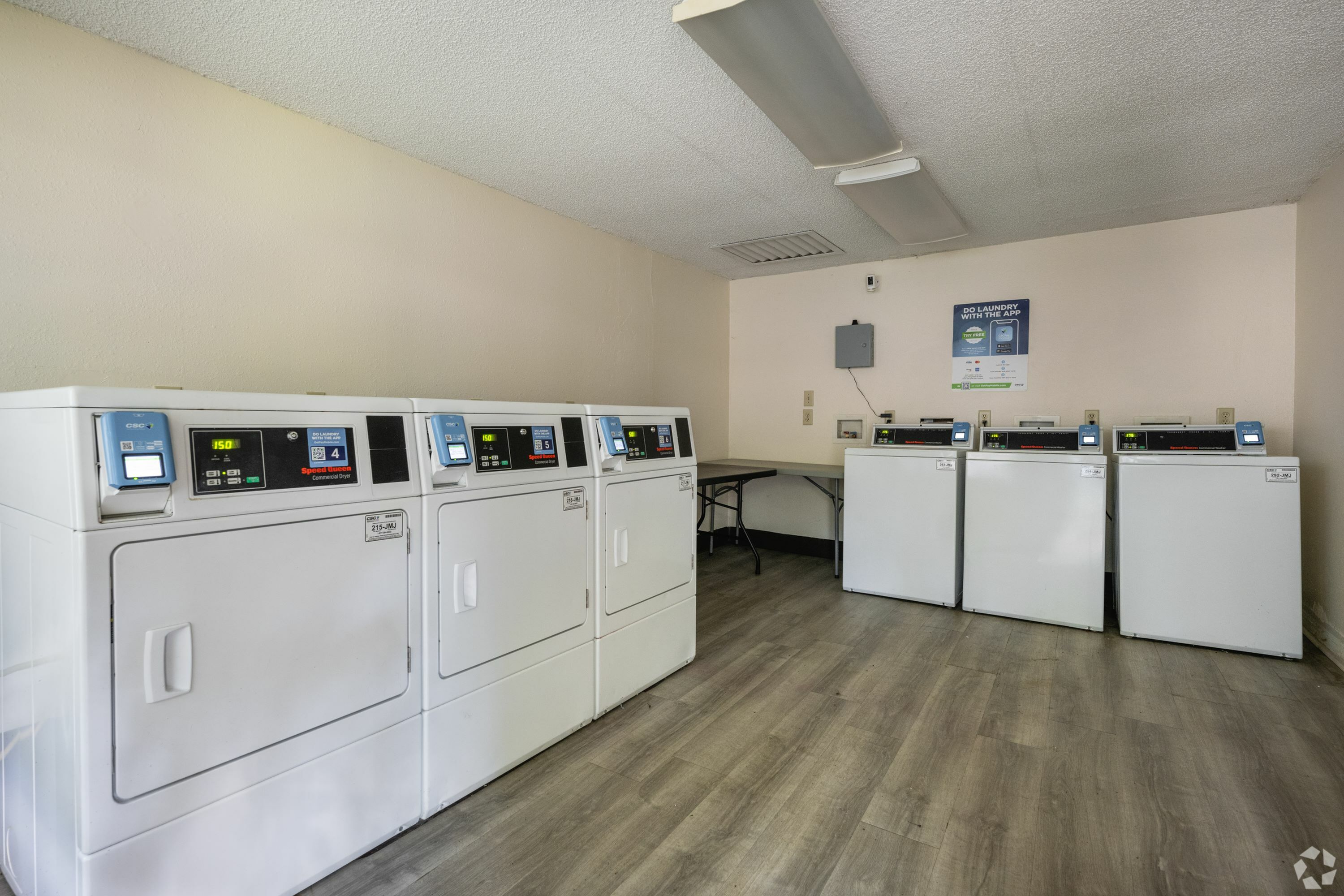 Bright and spacious laundry room featuring a row of modern washers and dryers on sleek flooring.