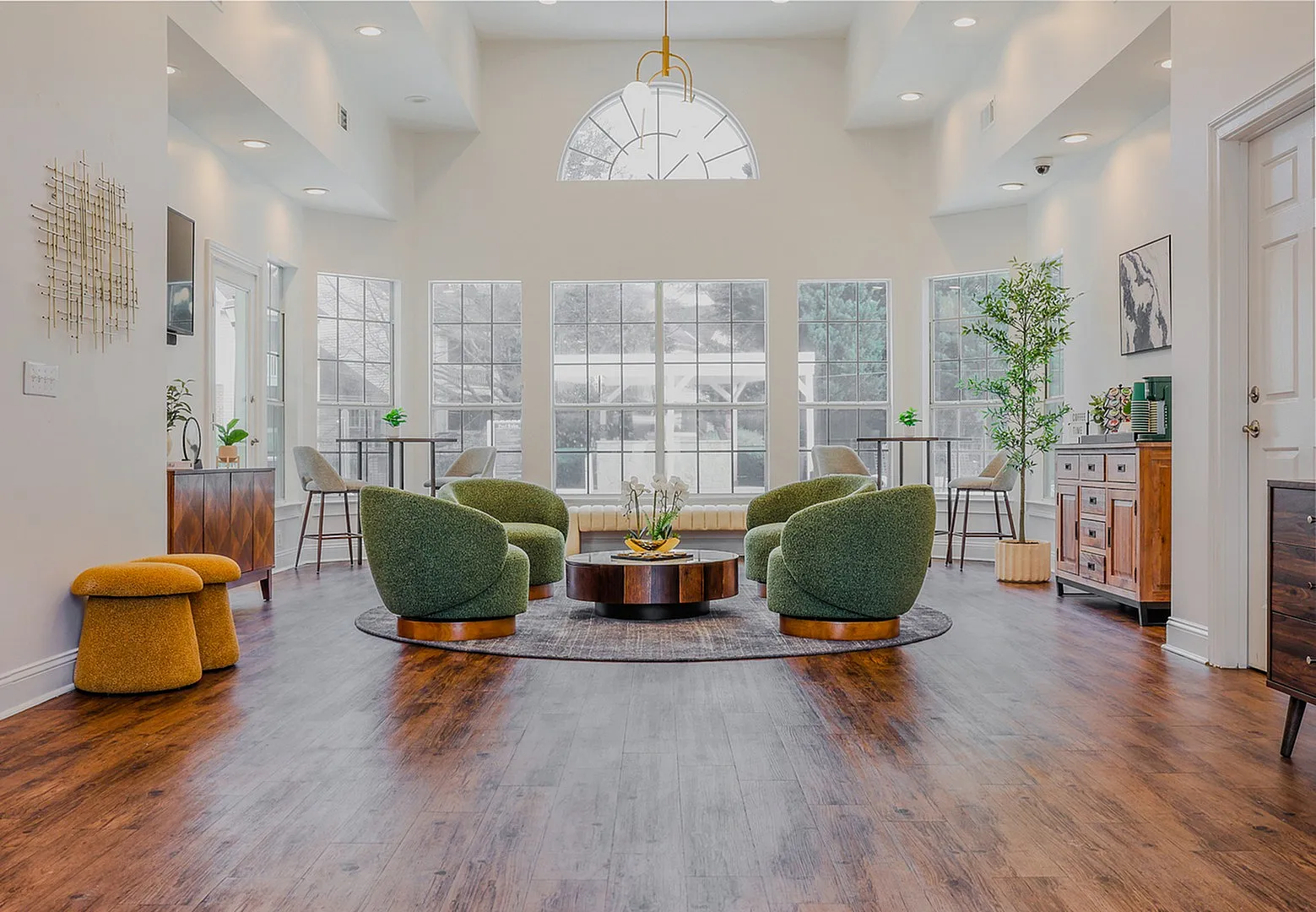 Bright and inviting clubhouse living room featuring a modern design, plush seating, and expansive windows overlooking a scenic courtyard. A welcoming space designed for relaxation and gathering