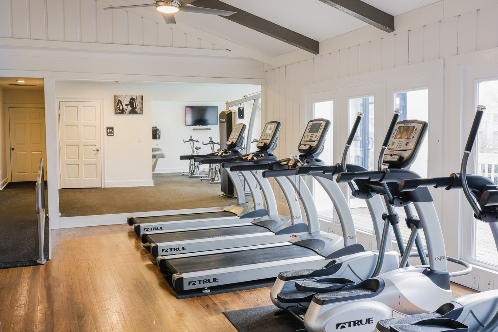 Modern fitness center with state-of-the-art cardio equipment and large windows for natural light.