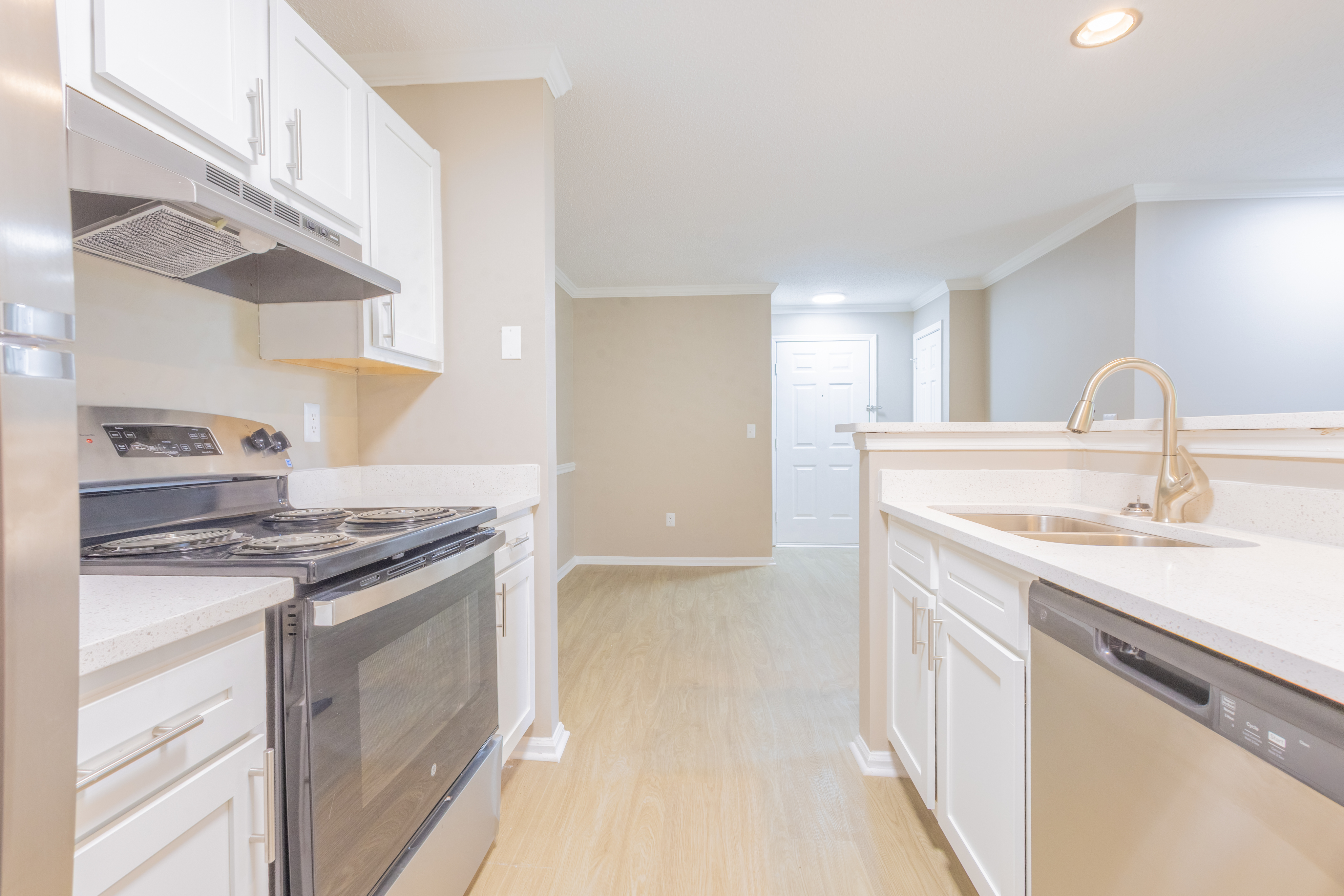 Bright and modern kitchen with sleek stainless steel appliances, pristine white cabinetry, and elegant wood flooring.