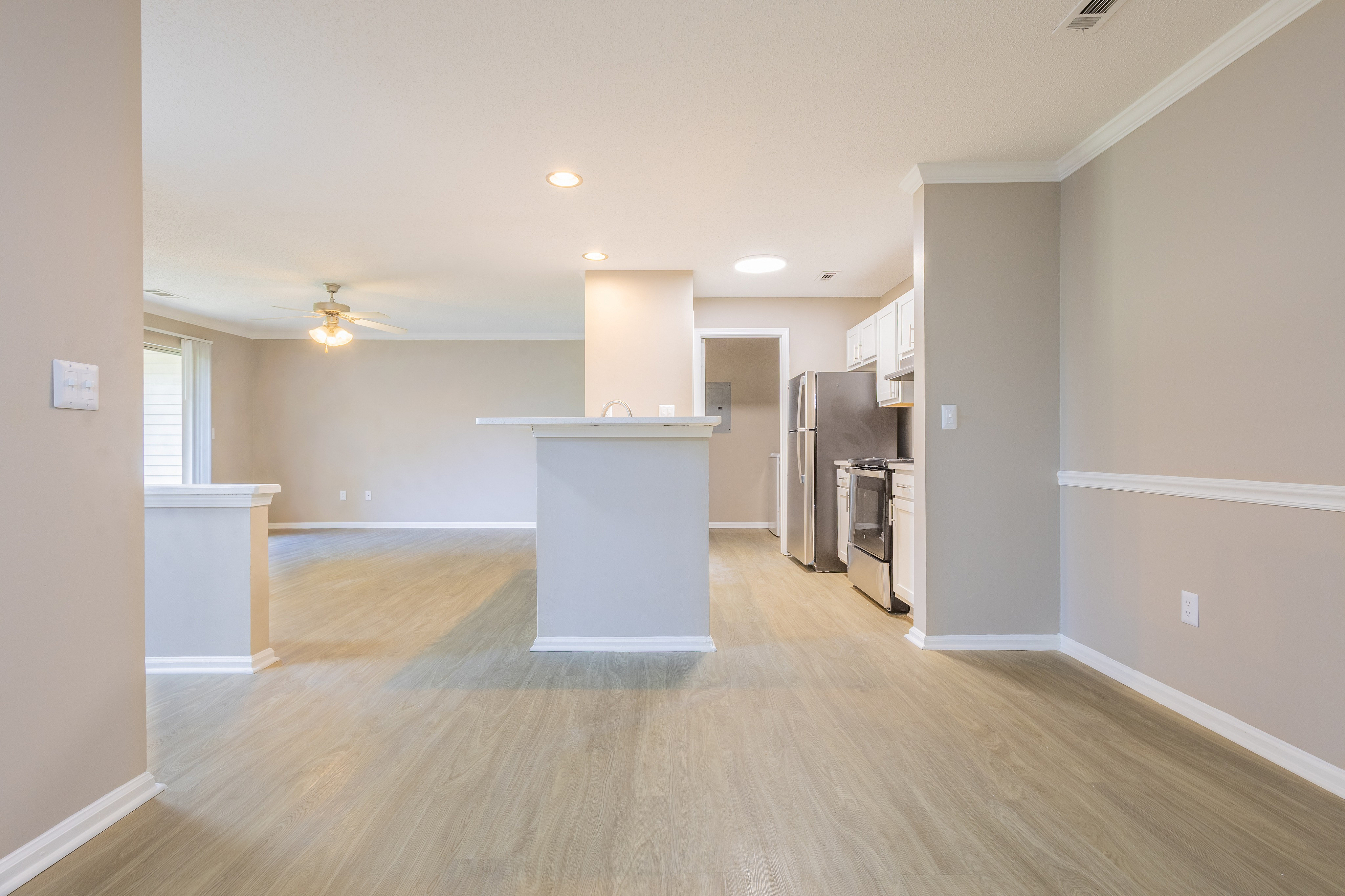 Bright open-plan apartment showcasing a modern kitchen, sleek hardwood floors, and a welcoming living area with natural light.