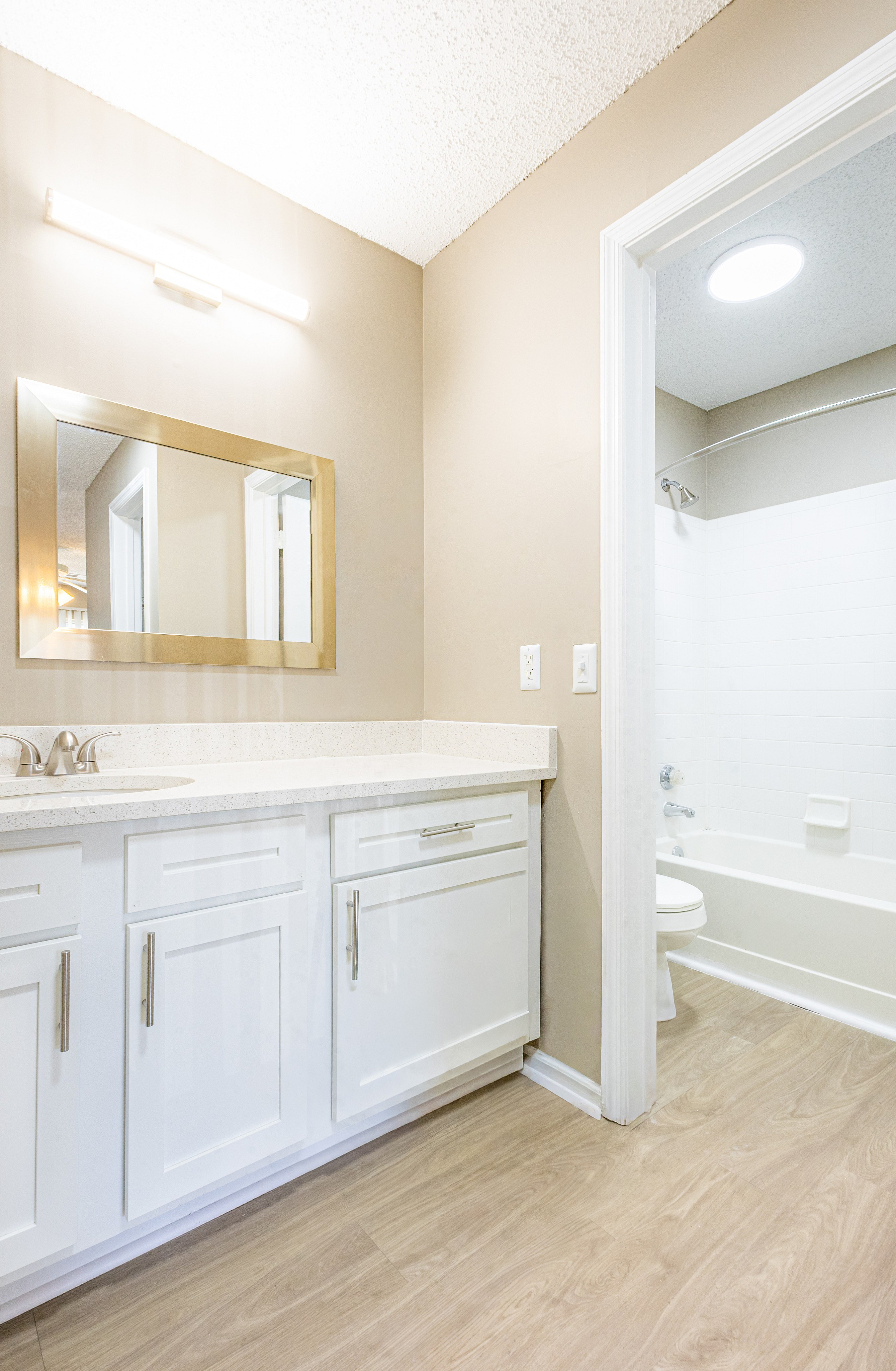 Bright and modern bathroom featuring sleek white cabinetry, a stylish mirror, and a pristine bathtub.