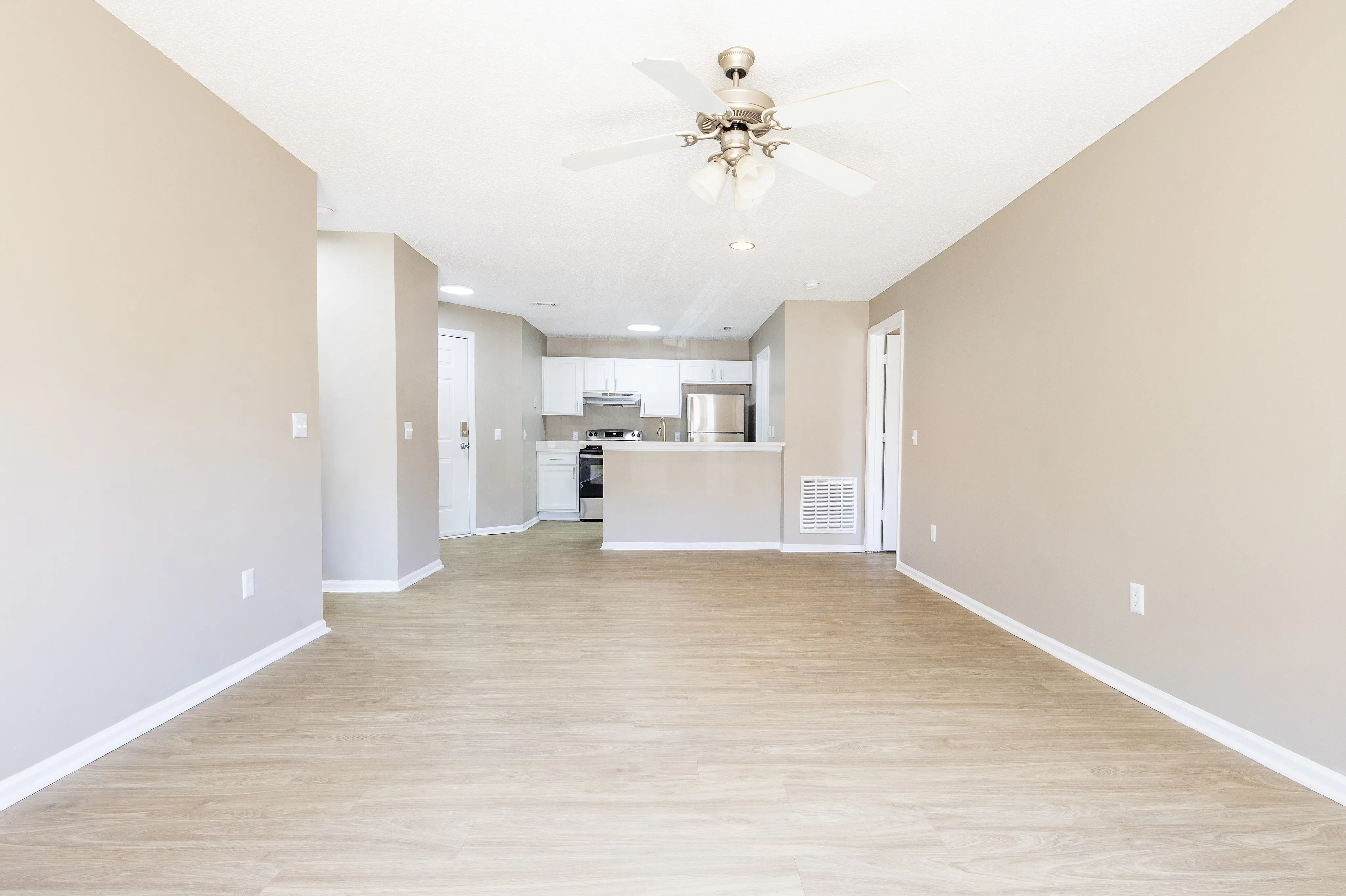 Spacious open-concept living area with modern kitchen and sleek hardwood floors, perfect for contemporary living.