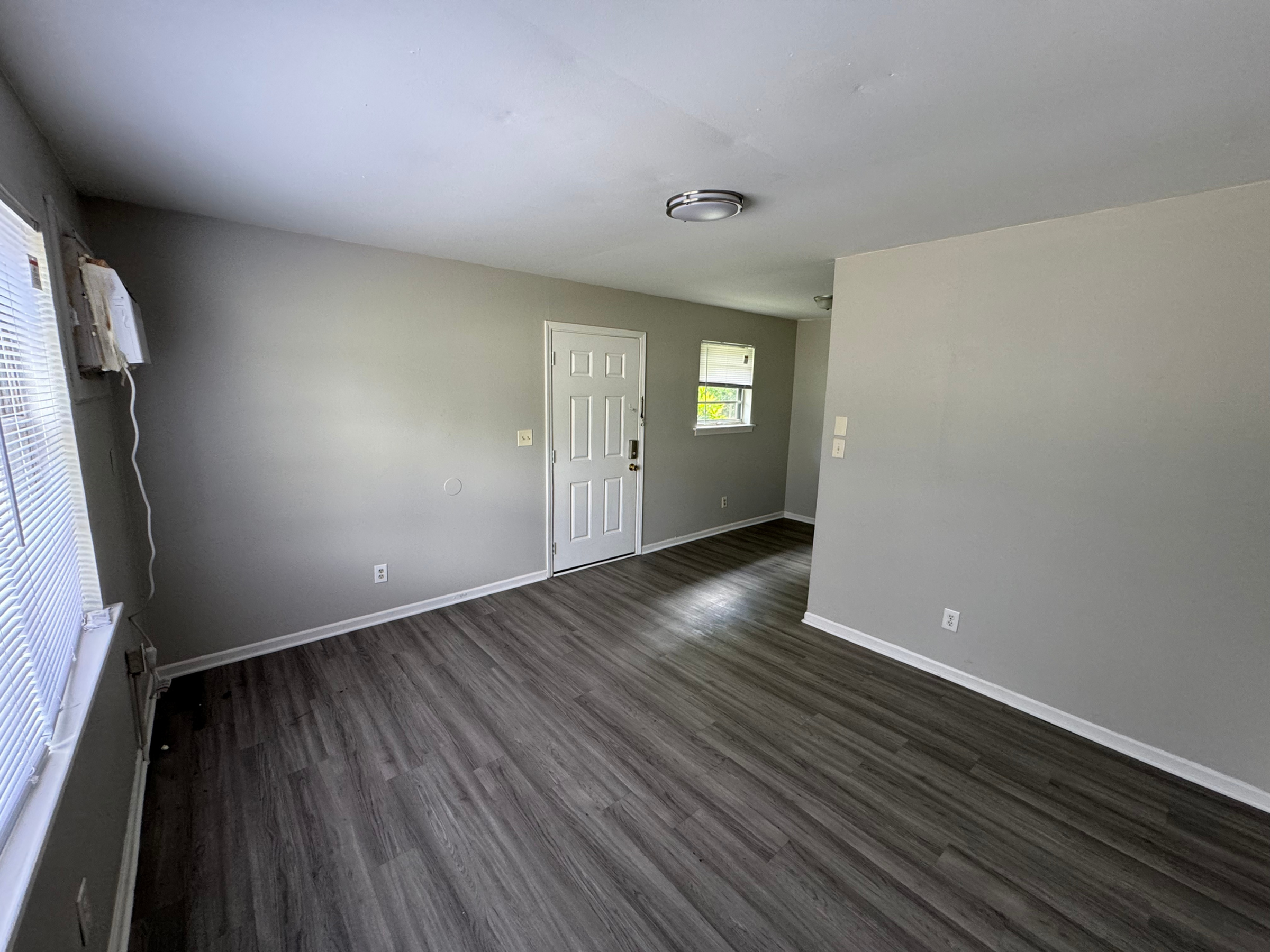 Bright and spacious living area with modern gray flooring and ample natural light, perfect for a comfortable home environment.