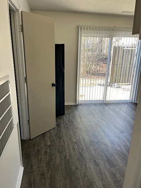 Bright apartment featuring sleek wood flooring, open layout, and large sliding glass doors leading to a serene outdoor space.