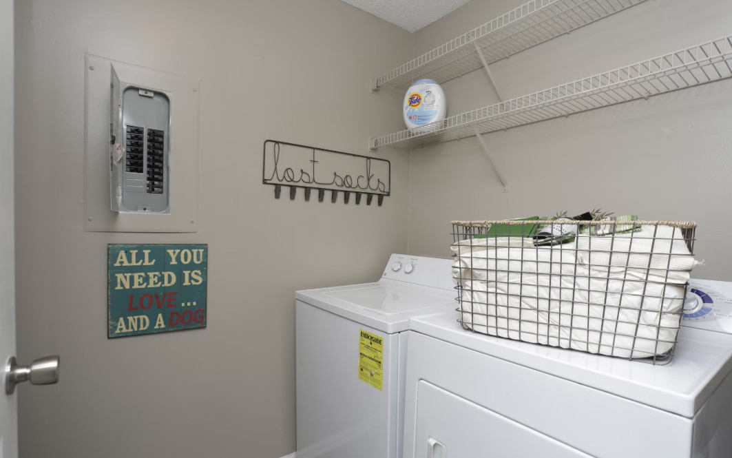 Cozy laundry room with modern washer-dryer, charming decor, and ample shelving for storage.