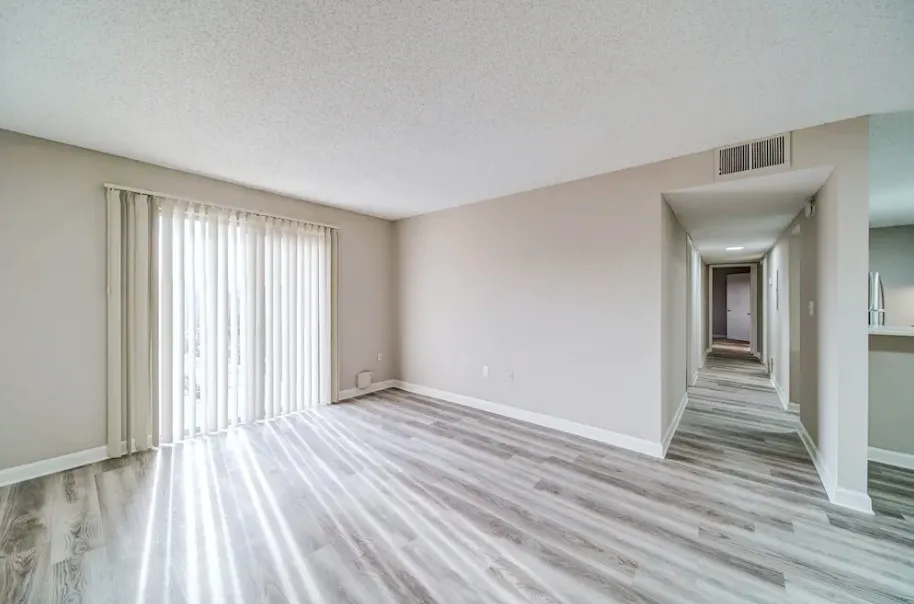 Bright and airy living space with elegant wood flooring and expansive hallway in a modern apartment.