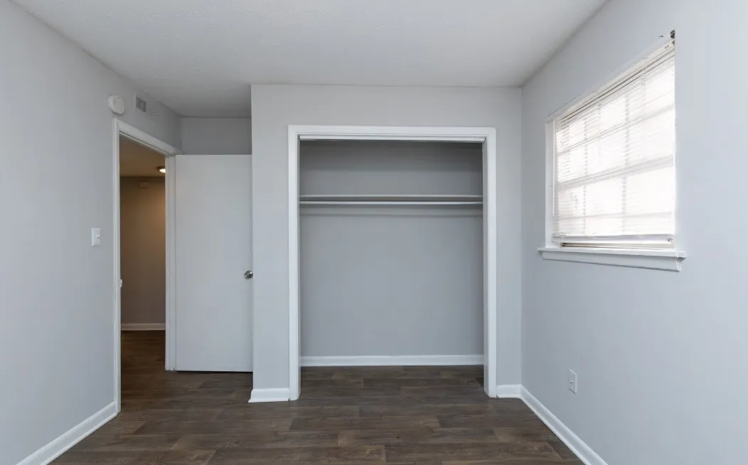 Bright bedroom with sleek hardwood floors and a large built-in closet, perfect for modern living.