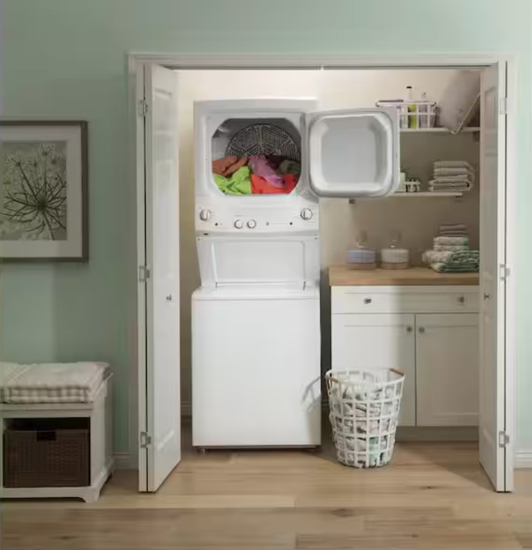 Compact laundry nook with stylish folding doors, featuring a stacked washer and dryer, ample storage shelves, and chic decor.