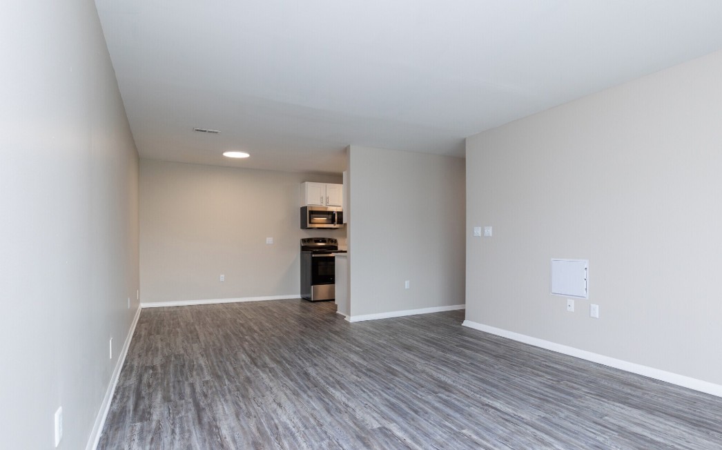 Sleek open-plan apartment with modern kitchen and spacious living area featuring elegant wood flooring.