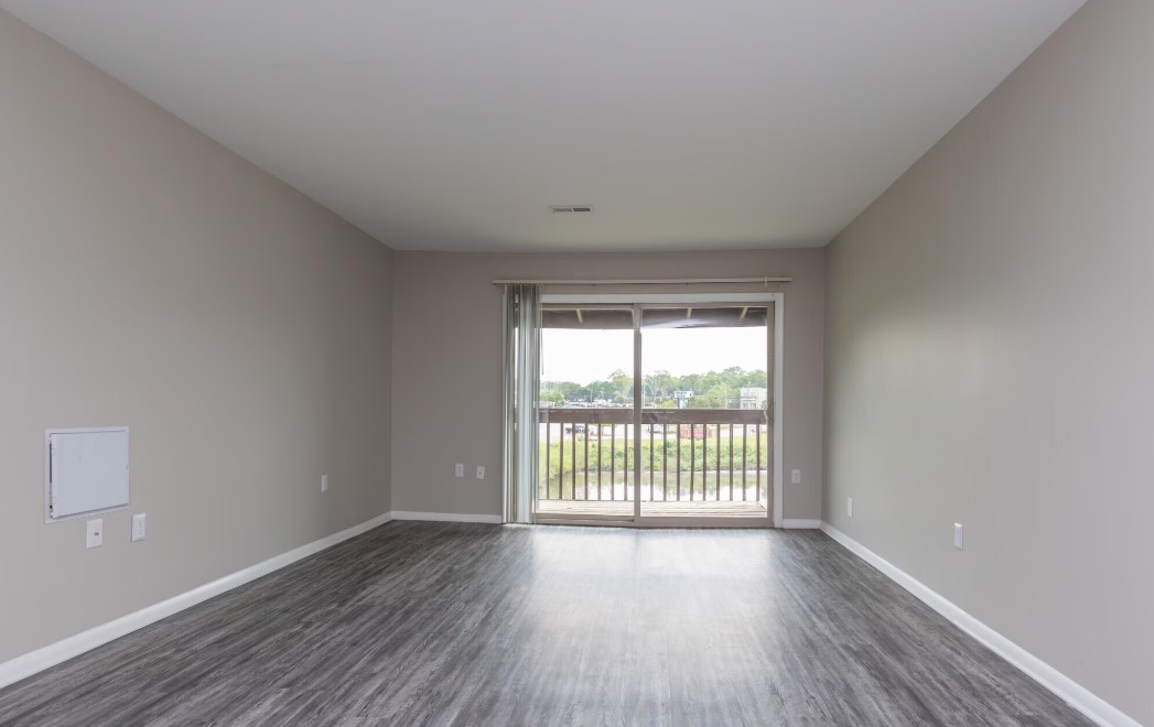 Bright and spacious room with sleek laminate flooring and large balcony window offering serene views.