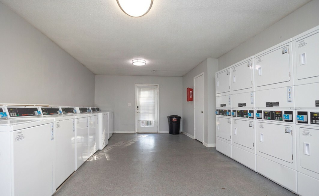 Bright and spacious laundry room equipped with multiple modern washing machines and dryers, perfect for convenient living.