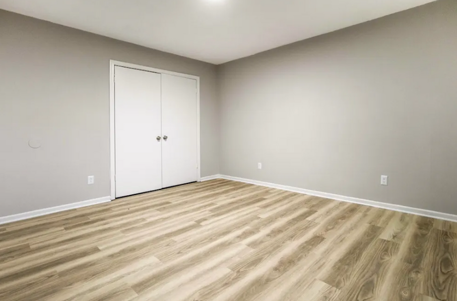 Bright, spacious room with elegant wood flooring and neutral walls, perfect for versatile living spaces.