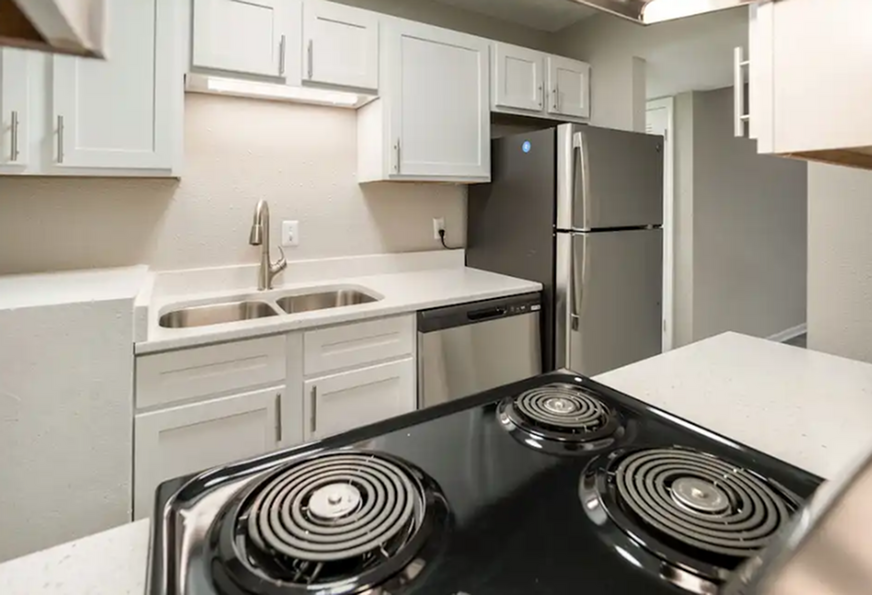 Modern kitchen with sleek stainless steel appliances, elegant white cabinets, and a spacious double sink.