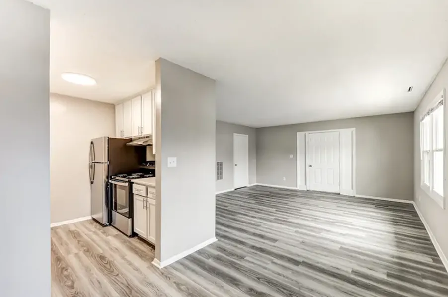 Bright and modern open-concept apartment with sleek hardwood floors, a compact kitchen, and ample natural light.
