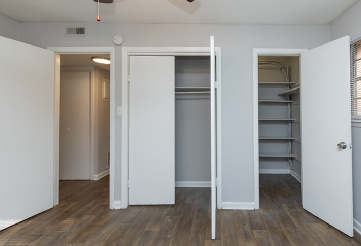 Charming room with dual closets and beautiful hardwood flooring, enhanced by sleek white shelving, perfect for modern living.