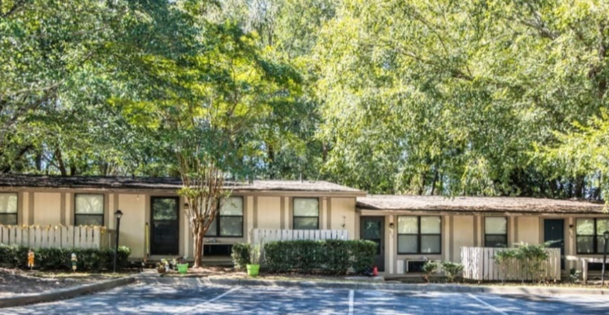 Charming single-story apartment complex surrounded by lush greenery, offering a peaceful and inviting atmosphere.