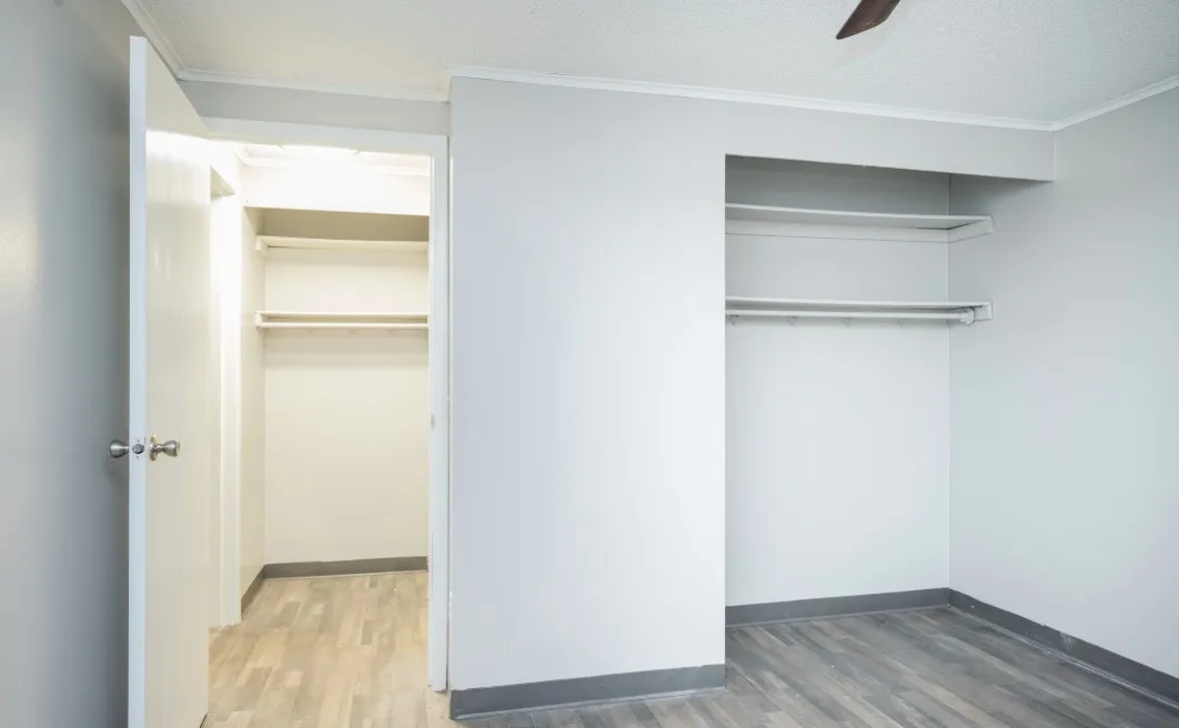 Spacious walk-in closet with sleek shelving and modern flooring, perfect for ample storage.