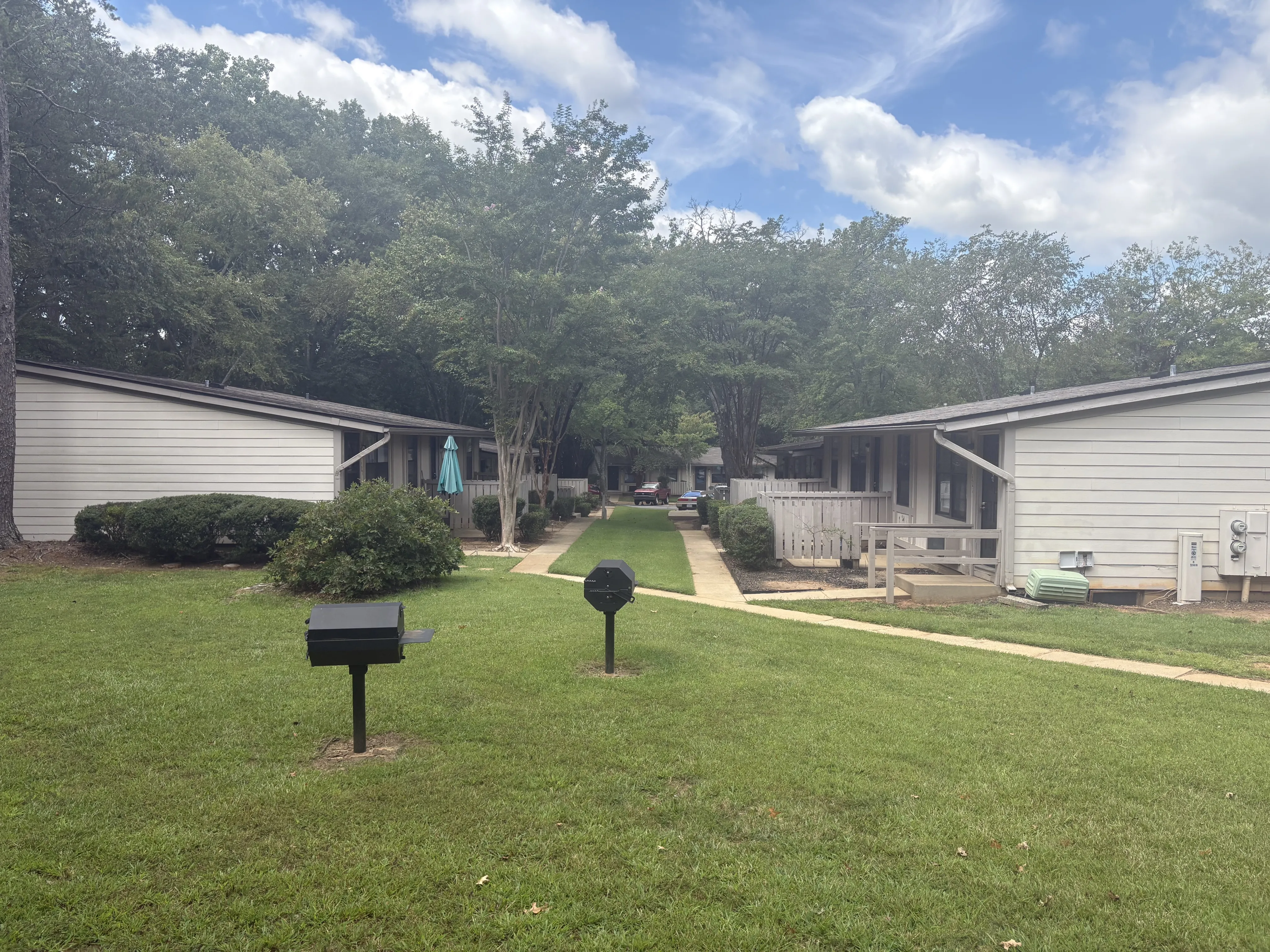 Charming residential community showcasing single-story homes with lush green lawns and a scenic pathway. Perfect for peaceful living.