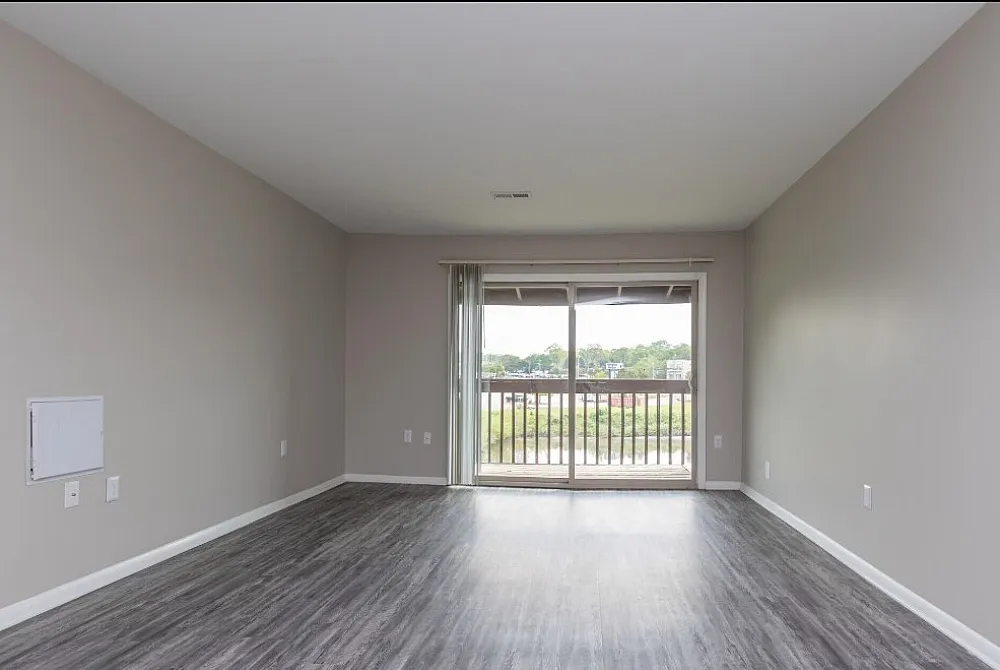 Bright and airy room with modern flooring and large window offering scenic views, perfect for a cozy lounge area.