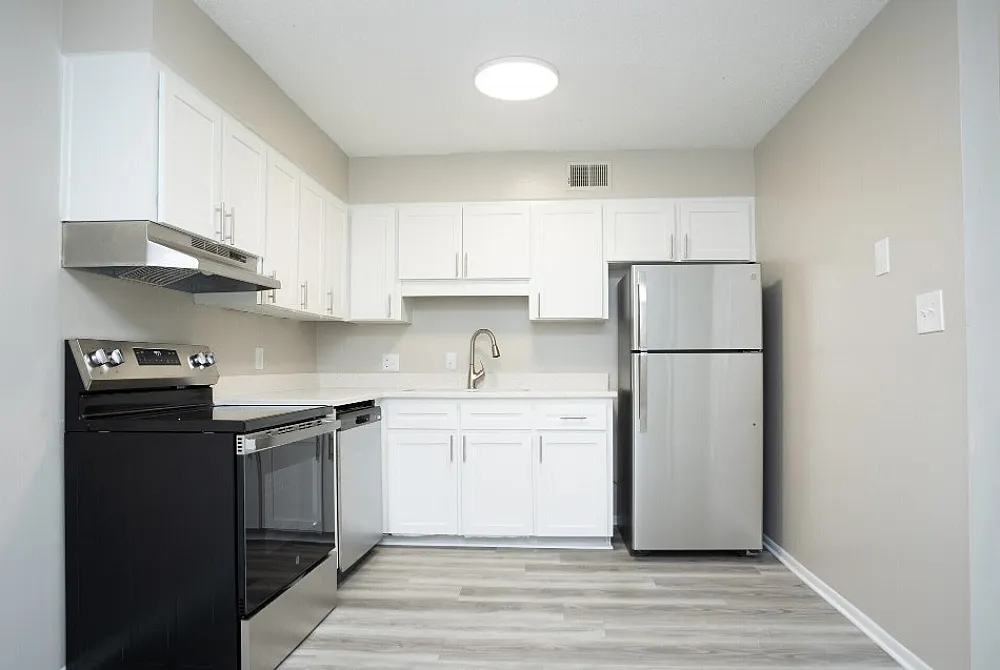Sleek modern kitchen with stainless steel appliances, pristine white cabinets, and elegant countertops.