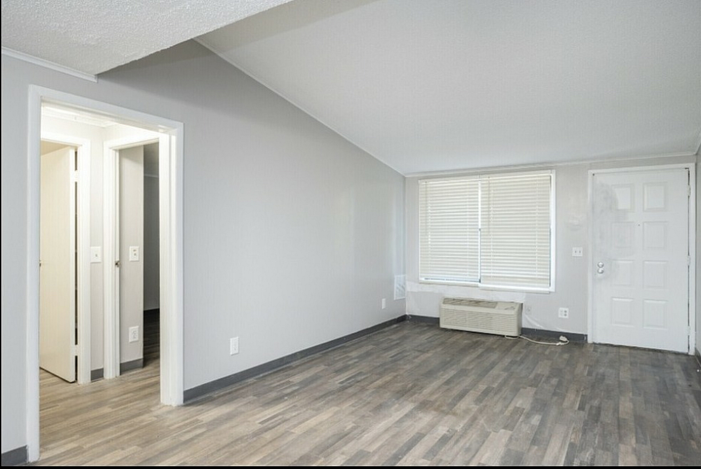 Bright and spacious living area with elegant wooden flooring and large window, offering a modern touch in a well-lit apartment.