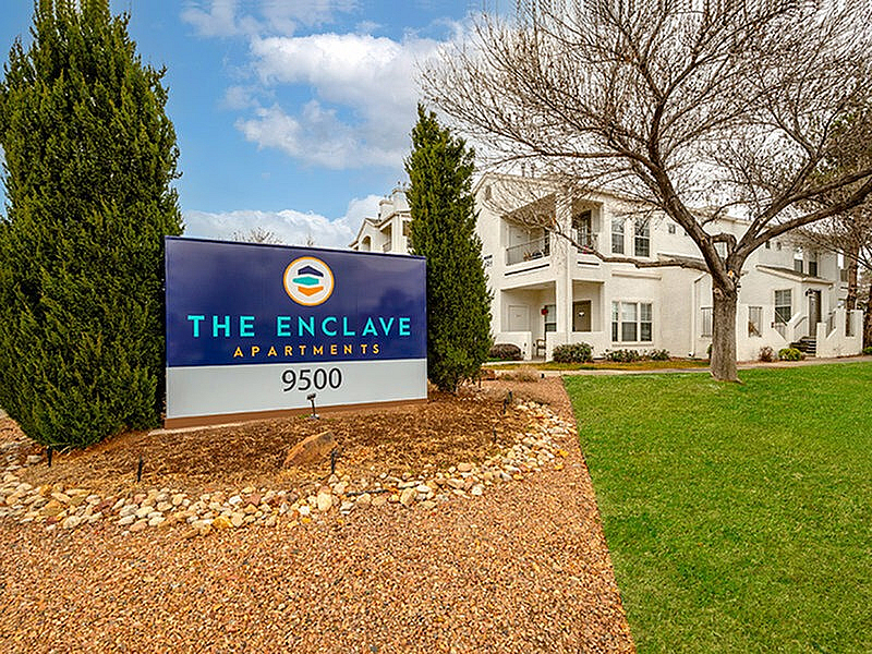 Charming exterior of The Enclave Apartments with lush greenery and modern architecture, offering a welcoming atmosphere.