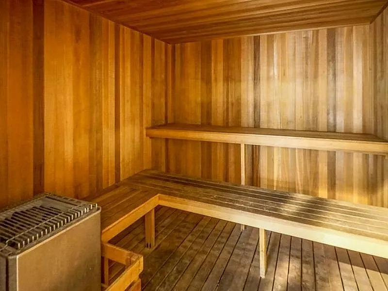 Inviting wooden sauna room with sleek benches and a state-of-the-art heater, offering a luxurious relaxation experience.