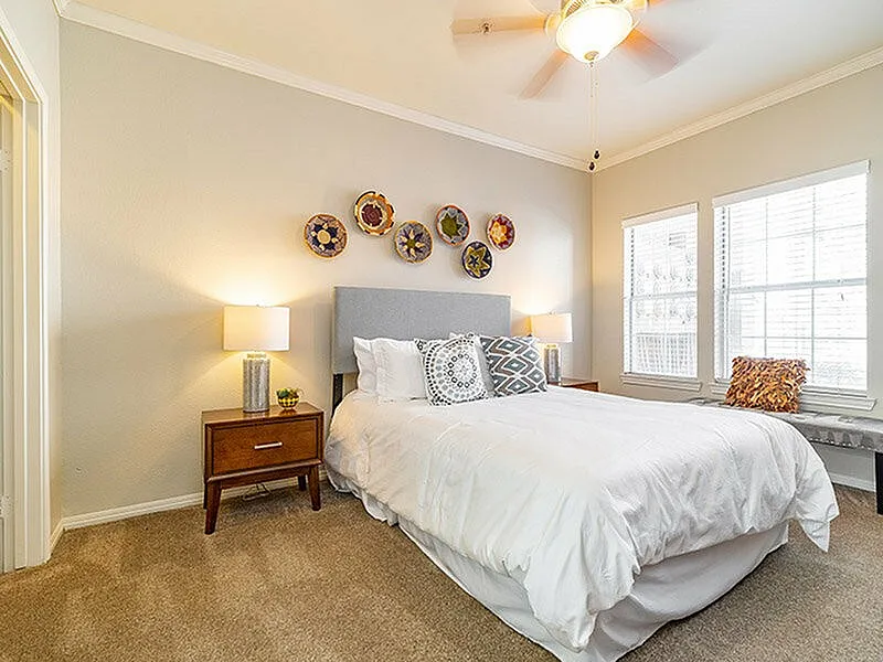 Bright and inviting bedroom featuring a comfortable double bed, stylish decor, and ample natural light from large windows.