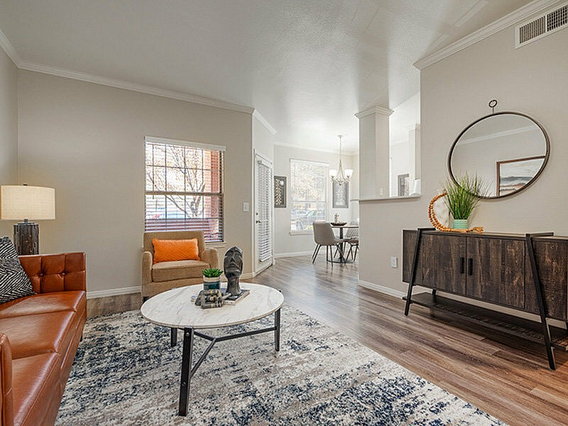 Inviting living space with elegant decor, featuring a cozy sofa, stylish armchair, chic coffee table, and a modern dining area, boasting abundant natural light and a warm, welcoming atmosphere.